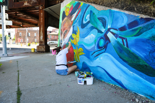 Metro Arts Youth student apprentice paining mural in Davenport