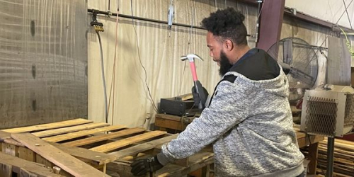 Worker deconstructing a wood pallet at Midland Davis Corp.