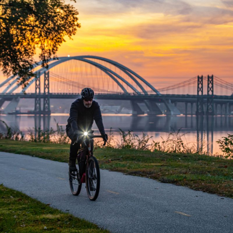 PErson riding bike at sunset along the Missisiippi River